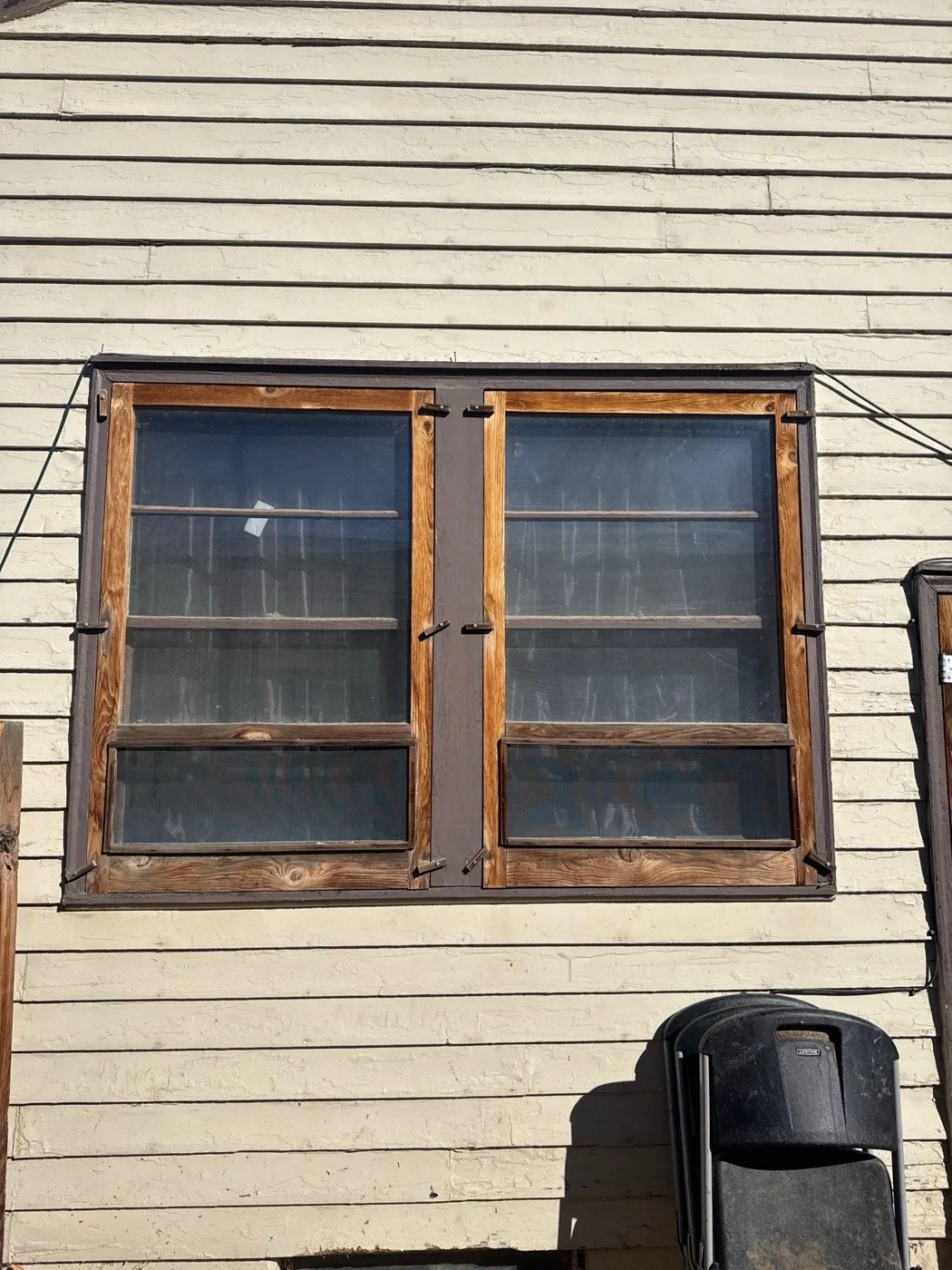 Original wood-frame window with peeling paint on an Englewood home, before replacement