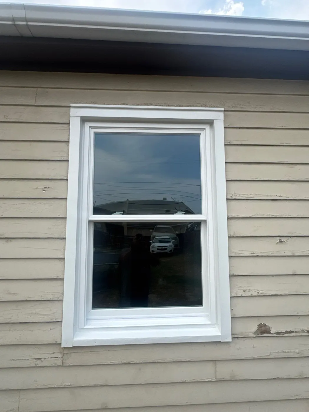 New white double-hung vinyl window with coil-wrapped trim on an Englewood home