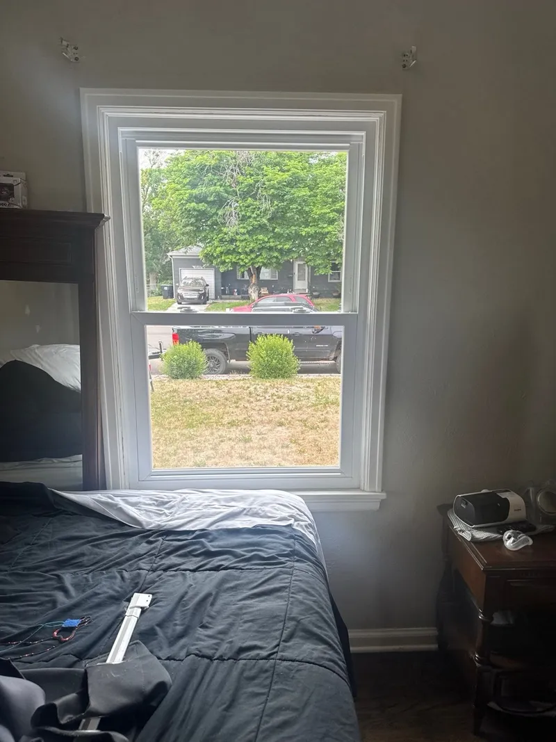 New double-hung window in a bedroom after installation, with fresh white interior trim